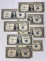 Top view of eight $1 U.S. silver certificate notes displayed in two rows, showing fronts with George Washington's portrait and blue Treasury seals.