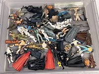 Overview of lot showing numerous Star Wars figures piled in plastic bin with some weapons and accessories visible