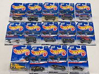 Overall lot view showing 14 Hot Wheels die cast cars in original sealed blister packaging arranged in rows including First Editions from 1996 and 1999.