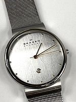 Front view of the Skagen men's wristwatch showing silver dial, dot hour markers, date window at 6, and silver mesh band.