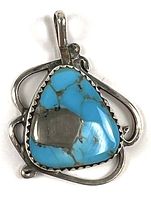 Front view of sterling silver pendant with bright turquoise stone featuring black veining and a silver patch in the center. Visible decorative silver swirls around the stone.