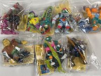 Seven Teenage Mutant Ninja Turtles action figures individually bagged with accessories and character info cards visible, showing condition and included items.