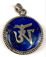 Front view of the circular pendant showing blue stone inlay and silver Om symbol with rope edge silver frame.