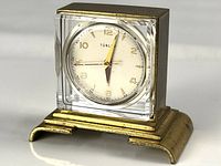 Front angled view of vintage Turler skeleton clock with visible clear crystal casing and brass base.