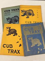 Four vintage yearbooks titled 'Cub Trax' with bear mascots and years printed on covers.
