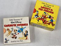 Photo of two slipcases for vintage Disney Little Treasury books: 'Favorite Stories' with white case, and 'Mickey & His Friends' with yellow case