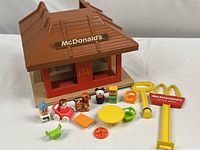 Photo showing building with all small figures and accessories spread in front including characters, furniture, and signage.