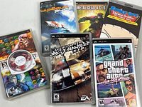 Overview photo of six PSP games displayed flat, showing front covers with various game titles and artwork.