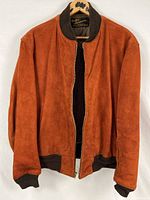 Front view of rust-orange suede leather jacket with ribbed crew collar and cuffs, hanging open to show quilted lining.
