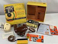 Contents of the vintage Zeiss Ikon Contina II camera kit including camera, case, flash unit, film accessories, slides, and original packaging box.