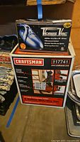 Craftsman wet/dry vacuum and Venus handheld vacuum in original boxes stacked on floor.