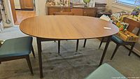 Front view of oval mid-century modern dining table with walnut veneer finish and tapered legs