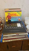 Stack of vintage vinyl records including Gene Autry's country album and a Star Wars original soundtrack album with black cover