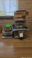 Stacked plastic bins and Webster boxes containing assorted hardware parts and tools