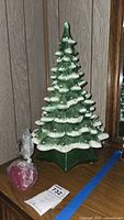 Front view of the vintage ceramic Christmas tree with red bird pegs bag beside it on wooden surface
