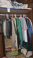 Full closet view showing hanging vintage clothing items including shirts, pants, and belts, folded items below