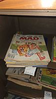 Stack of vintage MAD magazines on a shelf showing colorful covers, one with a man and lion on the cover