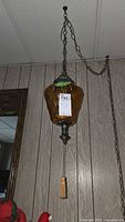 Full view of the vintage hanging lamp suspended from chain, showing amber glass shade and pull chain tassel.