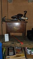 Wooden shoe shine box with drawer and red-handled back scratcher shoehorn on top of wooden surface