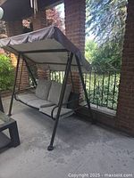 Full view of metal porch swing with canopy and cushions