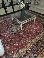 Full view of red Persian Kashan rug under glass coffee table