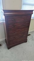 Front view of tall cherry-stained 5-drawer chest