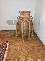 Full view of vase against wall and floor