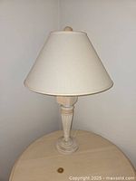 Full view of one cream table lamp with shade and base