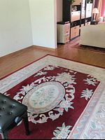 Full view of rug showing red field, ivory border, oval center medallion