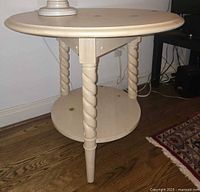 Full view of round light wood side table with spiral legs and lower shelf