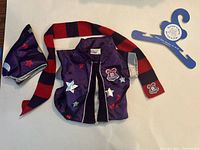 Purple vest, wizard hat, and striped scarf arranged with blue hanger