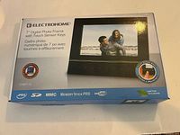 Front view of the original product box showing Electrohome 7-inch digital photo frame with touch sensor keys and compatible formats.