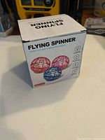 Box front showing flying spinner toy images and description 'Throw it out and fly back, it's automatic'