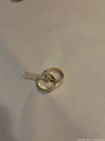 Two circular golden hoop earrings on a white background, showing their smooth polished surface and round shape.