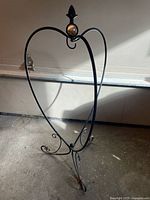 Full view of the black metal heart-shaped hanging plant stand showing the curved design and curled feet.