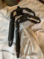 Pair of J Bar kayak roof racks showing foam padding and black metal frames laid on white fabric.