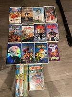 Photo showing 14 children's VHS movies arranged on floor, including titles The Swan Princess, Free Willy, Antz, The Land Before Time, E.T., Peter Pan, Toy Story, and others.