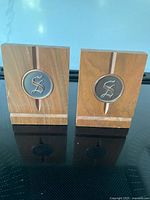 Front view of the pair of walnut bookends with silver circular monogram 'S' insets
