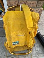 Yellow nylon hiking backpack shown from back with padded shoulder strap and metal frame.