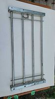 Photo of one metal adjustable window bar showing vertical and horizontal bars with lock mechanism.