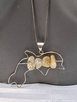 Clear front view of dolphin pendant pendant with four polished stones on 36 inch sterling silver box chain necklace.