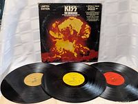 Front view of KISS The Originals Limited Edition triple LP records spread in front of cover showing album artwork and colored center labels.
