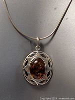 Close-up image showing the amber stone pendant and sterling silver setting.