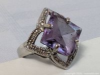 Close-up photo of sterling silver ring featuring a square-cut amethyst stone set in a beaded silver frame, showing chip on the stone and overall vintage condition.