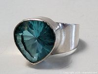 Close-up photo of the sterling silver ring showing the blue teardrop-shaped gemstone and the polished silver band from an angle.