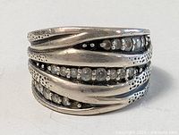 Front view of a wide sterling silver ring with hammered texture and embedded clear jewels arranged in recessed rows.