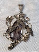 Front view of the sterling silver pendant featuring a teardrop jasper stone and intricate flower and leaf design.