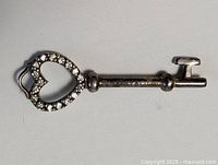 Full view of sterling silver heart-shaped key pendant with jeweled borders.