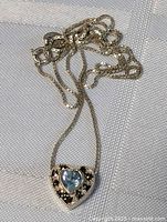 Full view of the necklace showing chain and heart pendant with aquamarine and marcasite stones, laid flat.