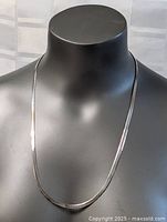 Full view of the necklace displayed on a black mannequin showing the length and drape.